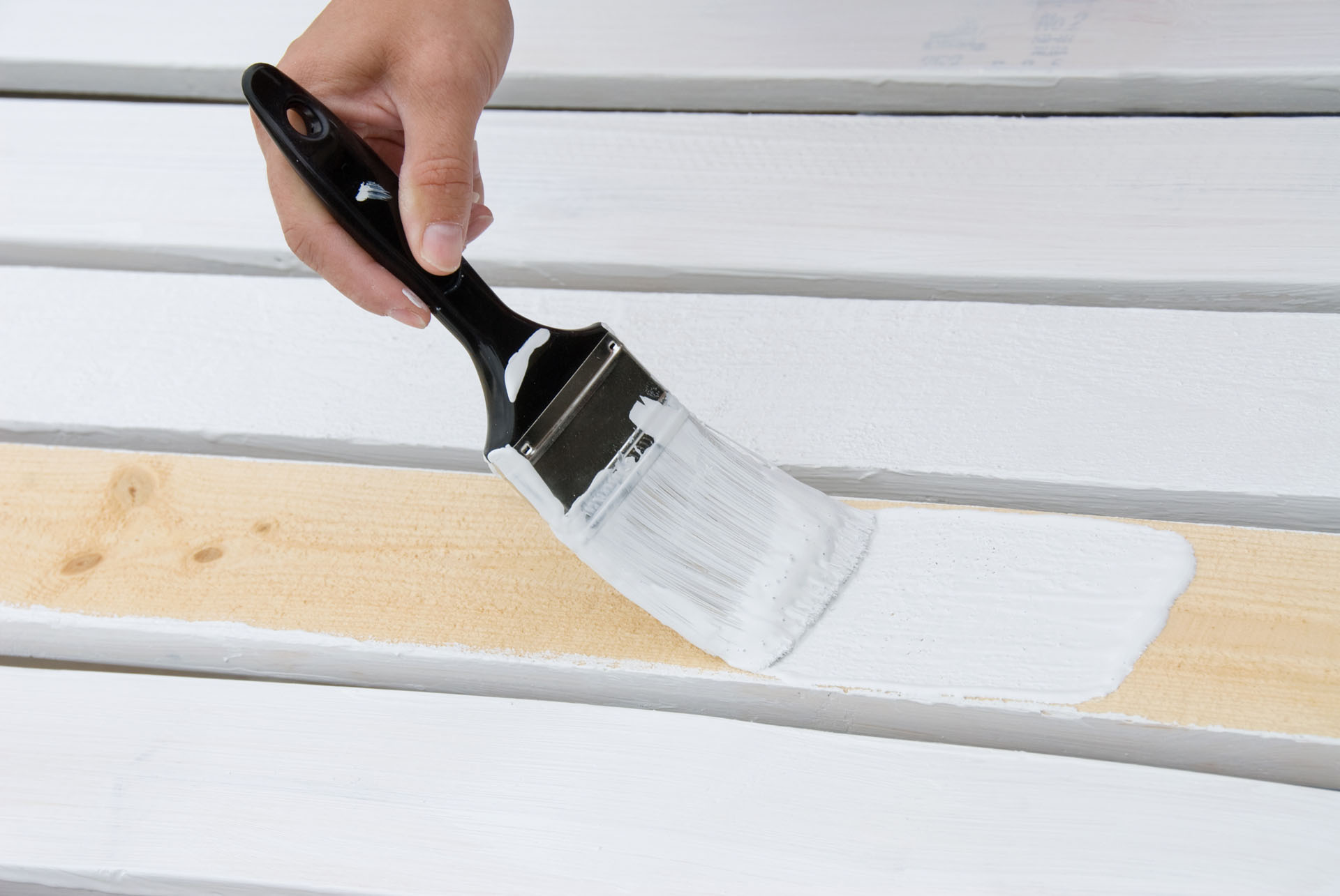 Hand painting wooden deck slats with white paint.